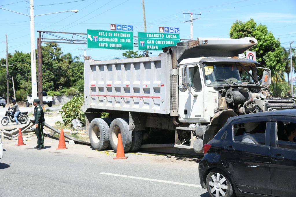 Camión volquete con daños en la parte delantera junto a conos y un agente en la autopista 6 de Noviembre.