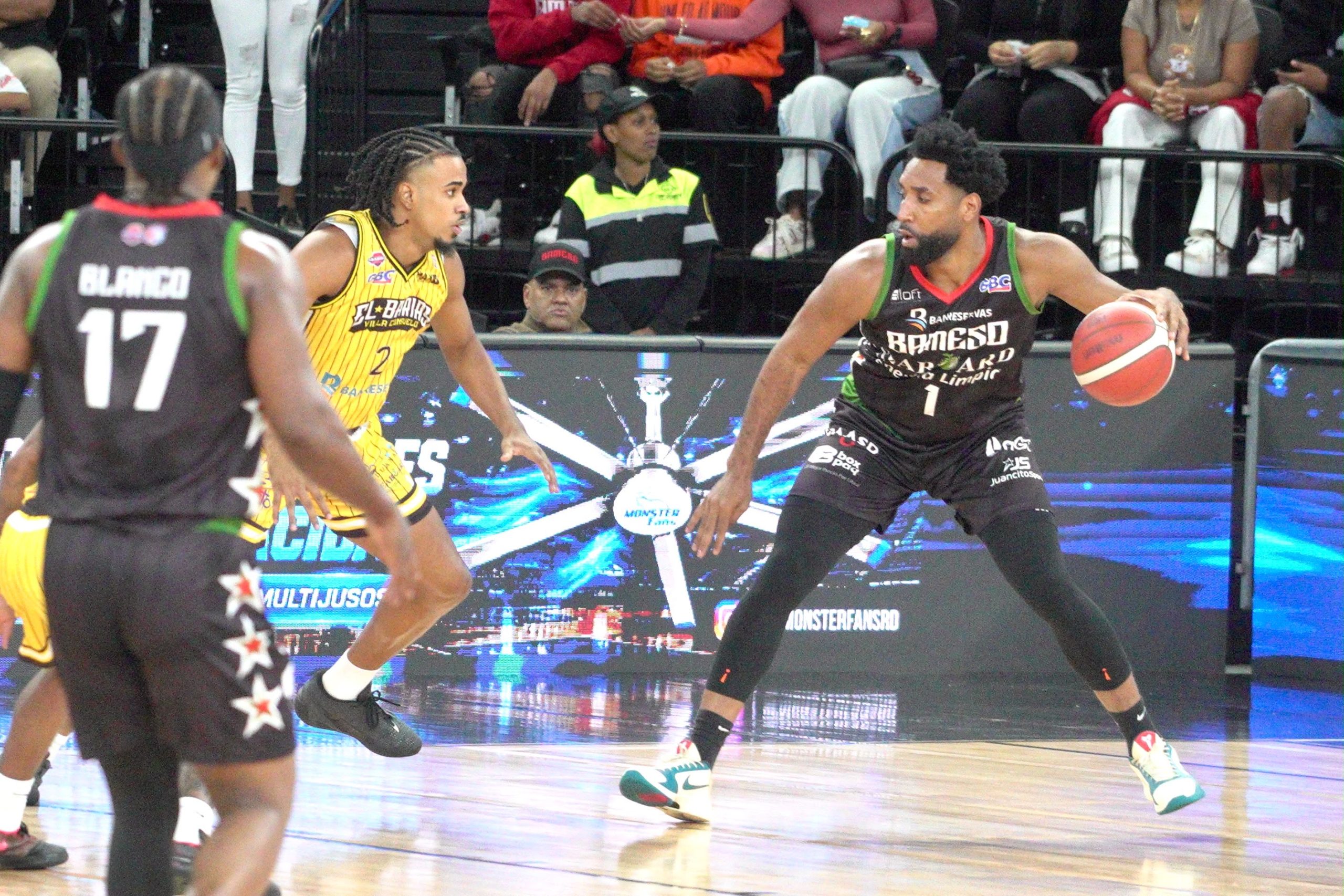 Jugador de Bameso maneja el balón frente a un defensor de Rafael Barias durante un partido de baloncesto.